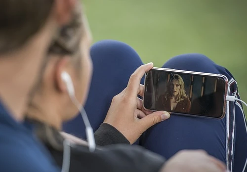 casal abraçado usando o fone e celular para assistir TV ao vivo